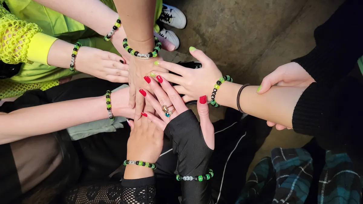 Knox KPop Girls dance team hands together in a huddle wearing KKG bracelets